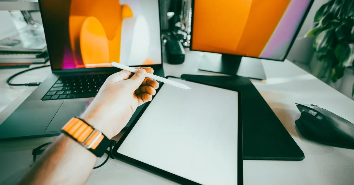 Espace de travail moderne avec un ordinateur portable, une tablette graphique et un stylet pour la création numérique.