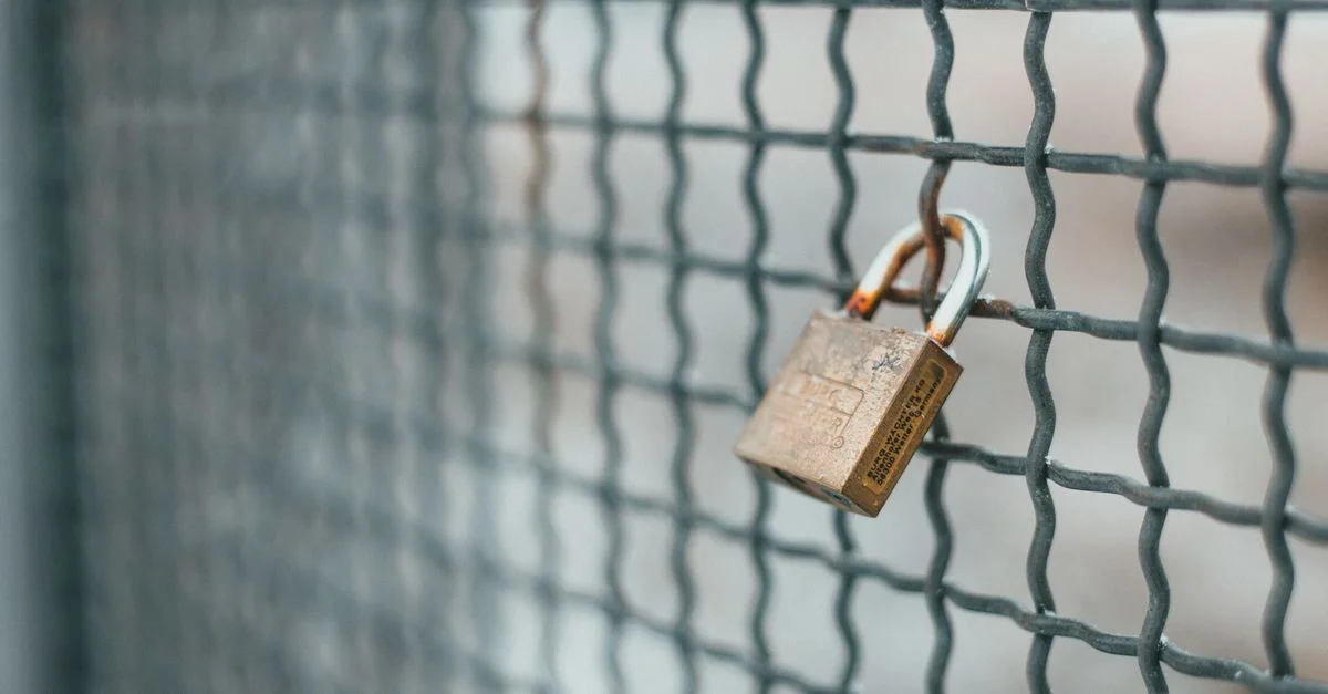 Gros plan sur un cadenas rouillé suspendu à une clôture en fil de fer à l'extérieur.