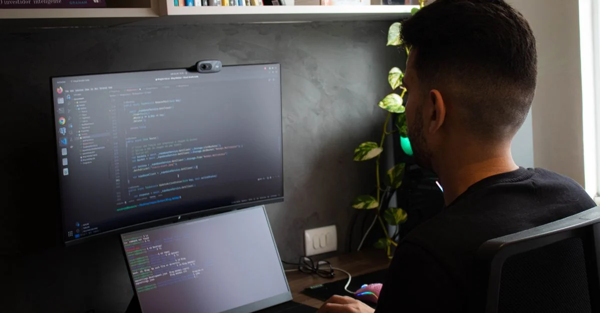 Un programmeur codant sur un ordinateur portable et un moniteur dans un bureau élégant.